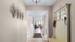 A hallway with a bench, a coat rack, and a wall-mounted decoration. - Sandy Toes l Oceanfront Condo l Heated Pool (St. Augustine)