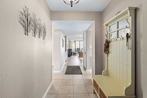 A hallway with a bench, a coat rack, and a wall-mounted decoration. - Sandy Toes l Oceanfront Condo l Heated Pool (St. Augustine)