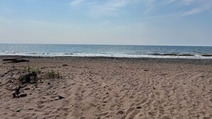 Ein Strand mit blauem Himmel, sandigem Ufer und ruhiger See.
