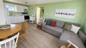 Ein kompakter Wohnbereich mit Küchenzeile, Essbereich und einer Sitzecke mit Sofa und Sesseln.