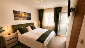 Une chambre à coucher moderne avec un lit, des tables de chevet, une commode, un tapis vert et une fenêtre avec des rideaux.