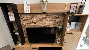 Un salon moderne avec un mur en pierre, un téléviseur à écran plat et une table basse en bois agrémentée de bougies et de plantes.
