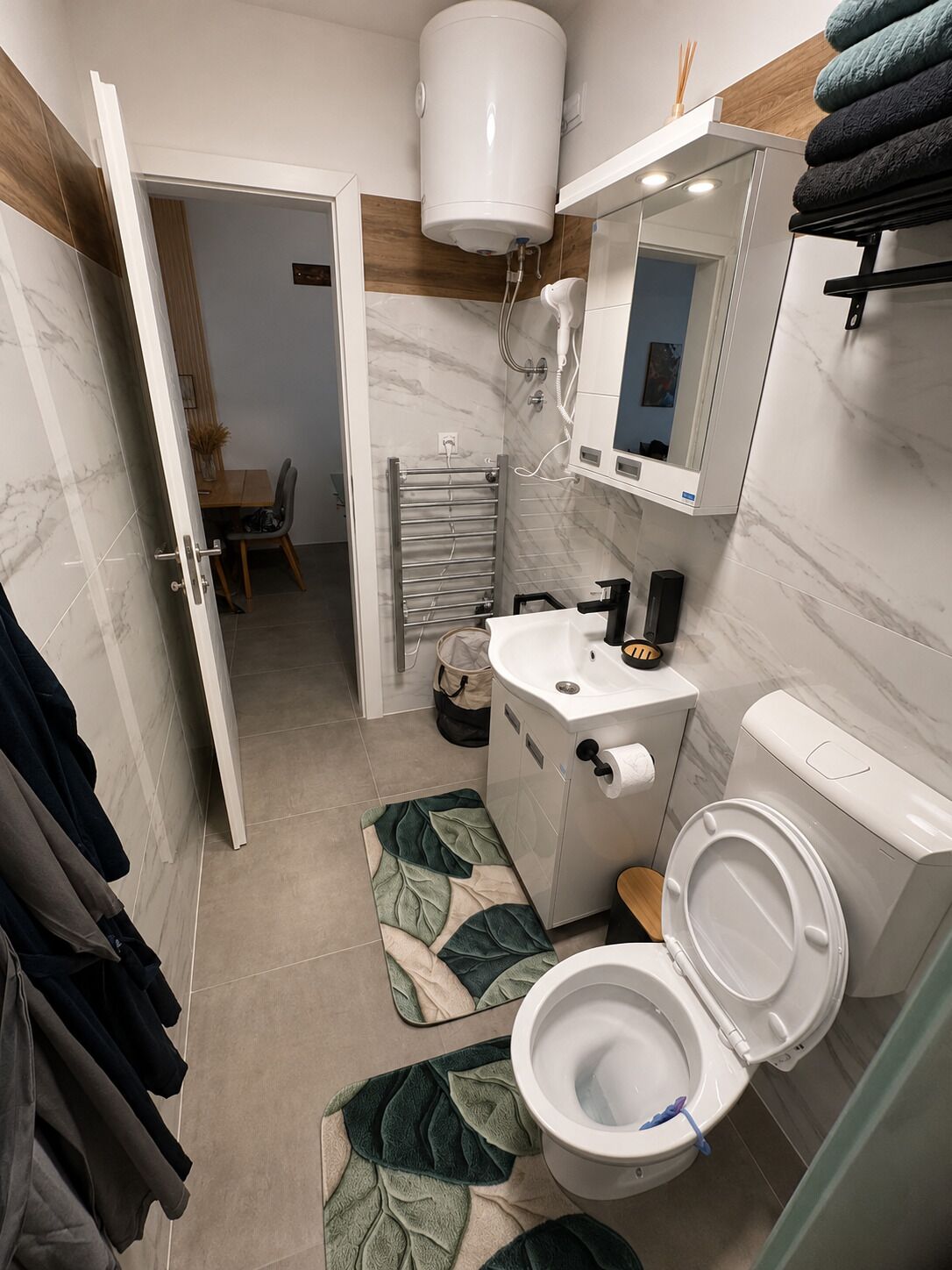 A modern bathroom with a toilet, sink, and towel rack.