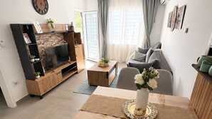 Un salon moderne avec un téléviseur à écran plat, une table basse en bois et un canapé.