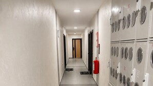 Un couloir bordé d’un côté de casiers et terminé par une porte.