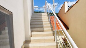 Eine Treppe führt zu einem Gebäude mit weißer Fassade und einer beige farbenen Wand auf der rechten Seite.