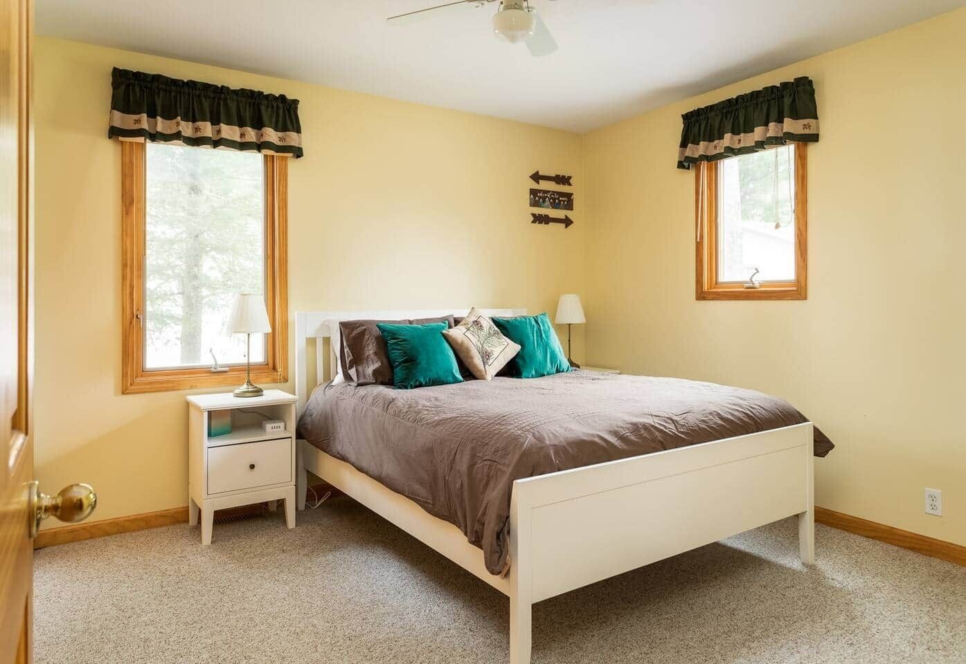 A bedroom with a bed, nightstands, and a window with curtains.