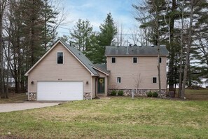 Ein zweistöckiges Haus mit Garage und Vorgarten.