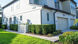 A two-story residential building with a white exterior, a front garage, and a well-maintained lawn. - Spacious 4-bedroom Townhome with AC in enchanting Davenport near Disney (Davenport)