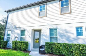 A two-story house with a front door, two windows with shutters, and a small porch area. - Spacious 4-bedroom Townhome with AC in enchanting Davenport near Disney (Davenport)