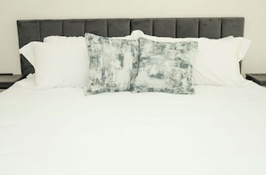 A bed with a grey upholstered headboard, white bedding, and two decorative pillows. - Spacious 4-bedroom Townhome with AC in enchanting Davenport near Disney (Davenport)