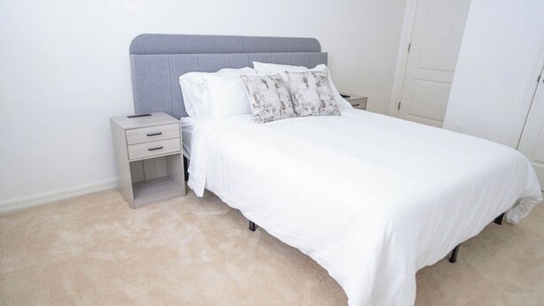 A bedroom with a bed, nightstands, and a carpeted floor. - Spacious 4-bedroom Townhome with AC in enchanting Davenport near Disney (Davenport)