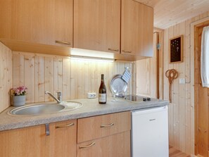 A kitchen with wooden cabinets, a sink, a wine bottle, and a dishwasher. - "Ingebore" - 500m from the sea by Interhome (Præstø)