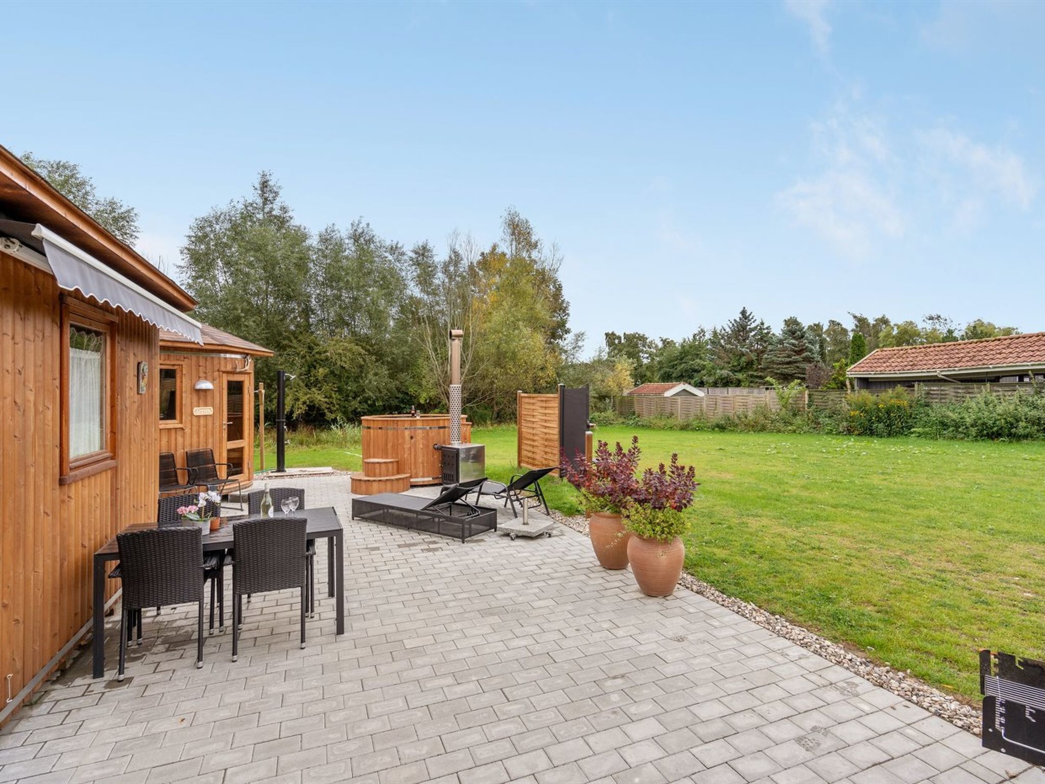 Une cabane en bois dotée d’un patio comprenant une table, des chaises et un barbecue.
