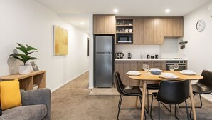 A modern kitchen with a dining area, a refrigerator, a microwave, and a clock on the wall. - Modern Townhouse  Walk to Hagley Park & Hospital (Christchurch)