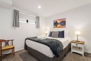 Ein Schlafzimmer mit Bett, Nachttisch, Stuhl und einem Bild an der Wand.