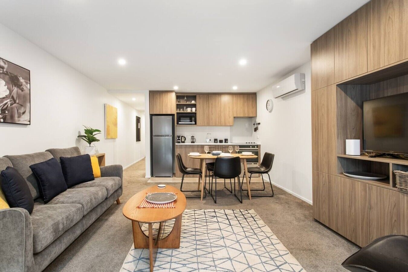 A modern apartment with a living room, dining area, kitchenette, and a TV on the right.