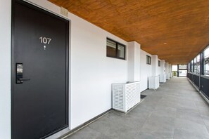 Ein Flur mit einer schwarzen Tür, auf der '107' steht, weißen Wänden und einer Holzbodenverkleidung.