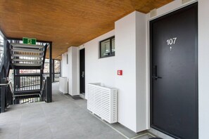 En gang med en sort dør markeret 107, en hvid radiator og en skilt til udgang.