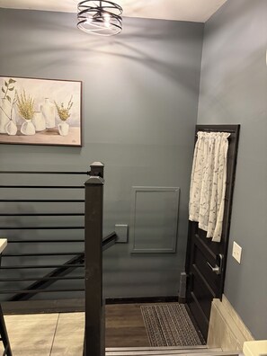 A bathroom with a grey wall, a painting of vases, a towel rack, and a door with a handle. - Delightful 3-bedroom house in Rapid City perfect for your getaway (Rapid City)