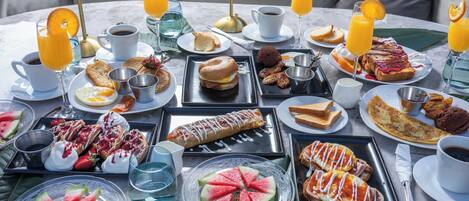 A breakfast buffet with various dishes, drinks, and a table setting.