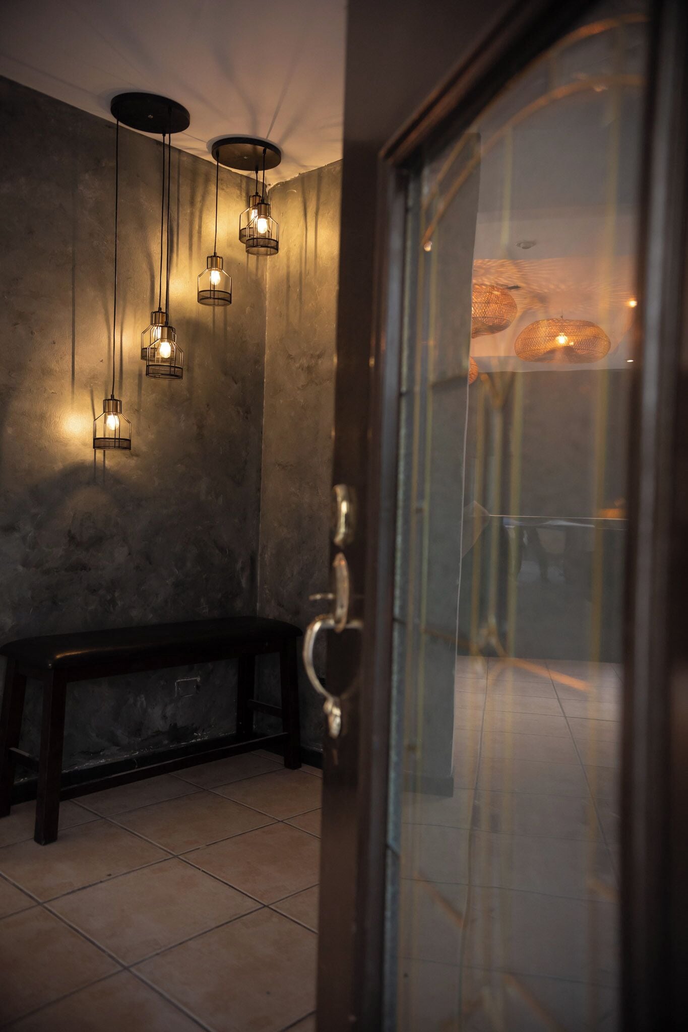A room with a bench, a door, and hanging lights.