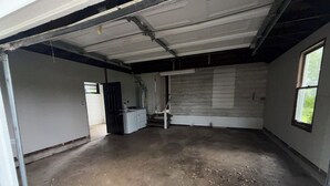 Sisätila, jossa on betonilattia, ovi, joka johtaa toiseen huoneeseen, ja ikkuna oikeanpuoleisessa seinässä.