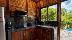 A modern kitchen with wooden paneling, a large window, and a view of greenery.