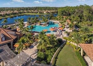 A resort with a swimming pool, palm trees, and a view of a lake. - Cozy 2-bedroom condo in delightful Naples with AC and fitness room (Naples)
