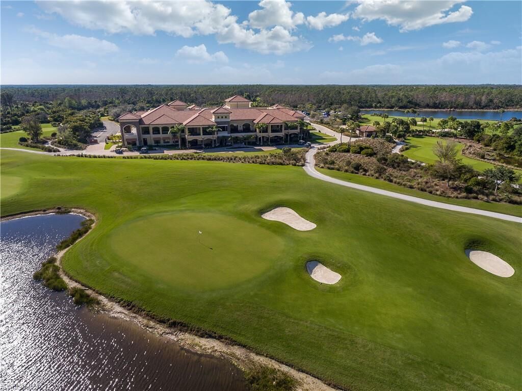 A golf course with bunkers and a large building with a red roof.