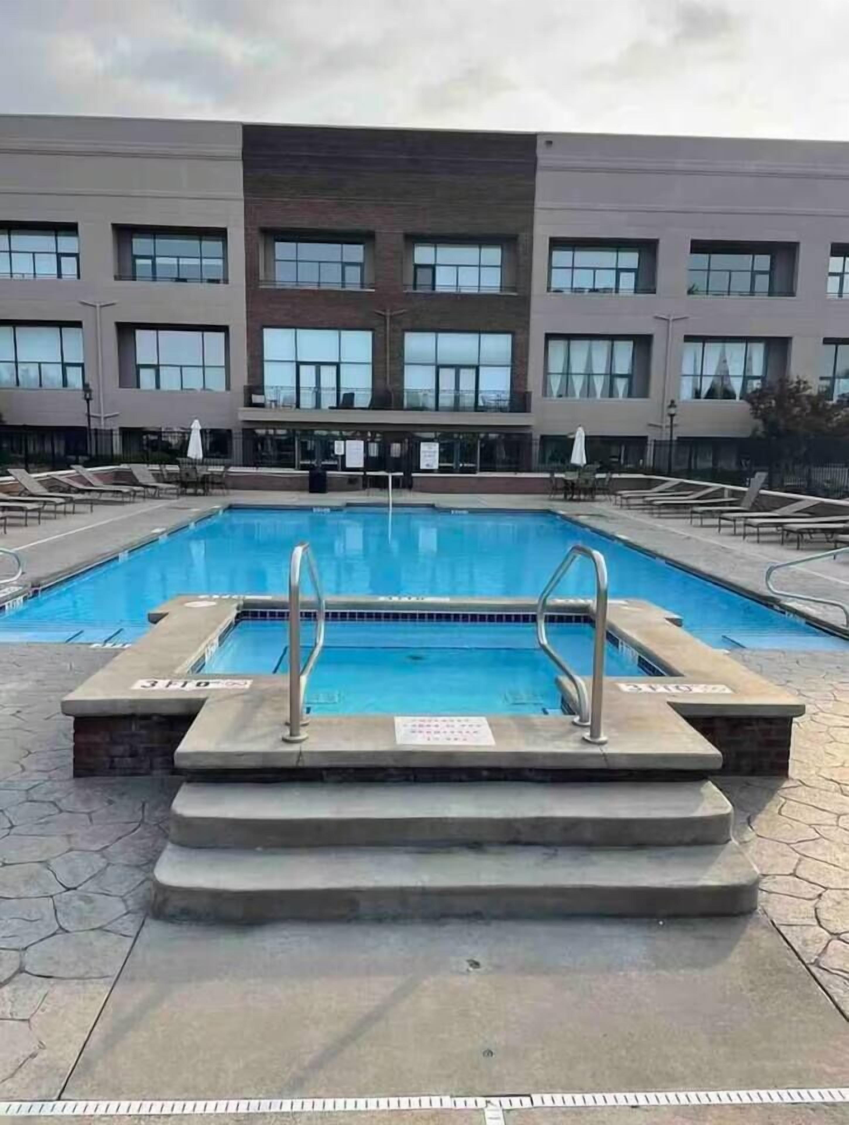 Une piscine rectangulaire avec des marches menant à l’eau, entourée de chaises longues et de parasols.