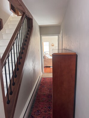 A staircase with wooden railings leading to a landing with a wooden desk.