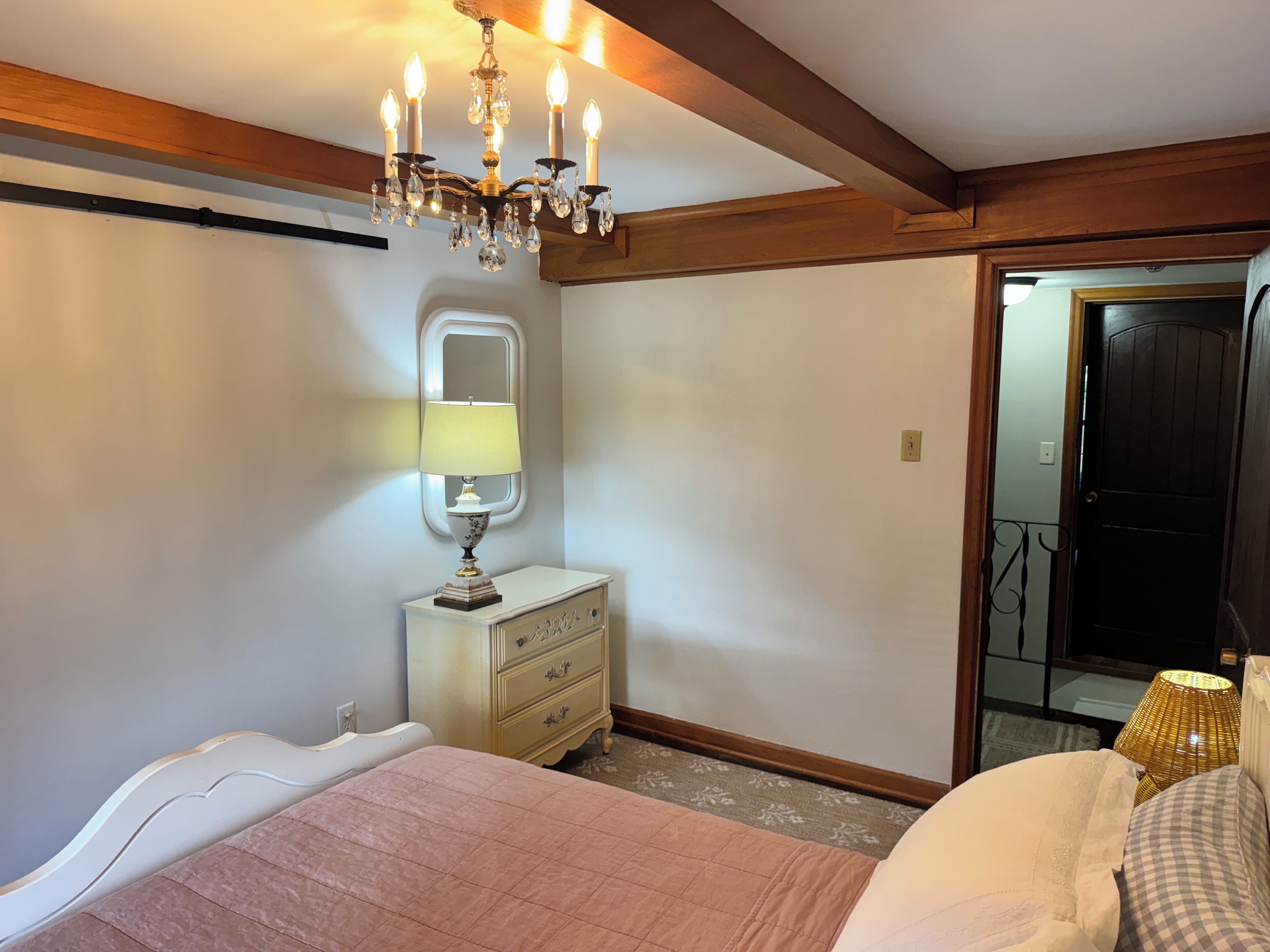 Een slaapkamer met een bed, een kaptafel, een spiegel en een kroonluchter.