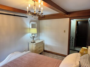 A bedroom with a bed, a dresser, a mirror, and a chandelier.
