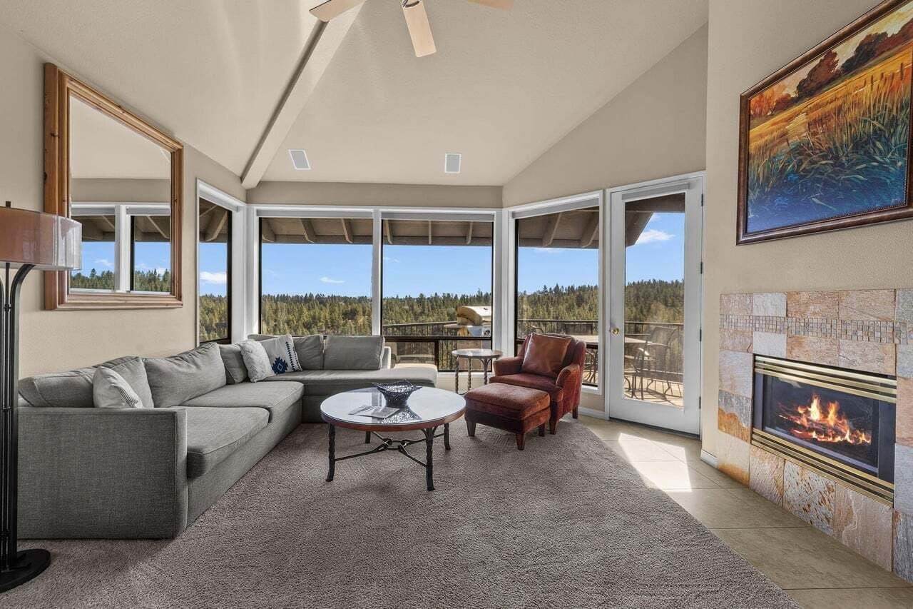A spacious living room with a large sectional sofa, a round coffee table, a leather armchair, and a fireplace.