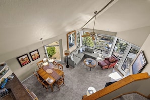 A spacious living area with a dining table, sofas, and a balcony with a view. - River Ridge 420A - Prime Westside River Views | Pool & Hot Tub (Bend)