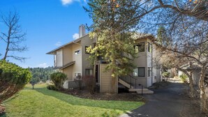 A two-story residential building with a covered porch and a visible staircase leading to the upper floor. - River Ridge 420A - Prime Westside River Views | Pool & Hot Tub (Bend)
