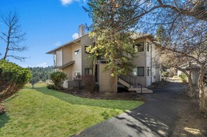A two-story residential building with a covered porch and a visible staircase leading to the upper floor. - River Ridge 420A - Prime Westside River Views | Pool & Hot Tub (Bend)