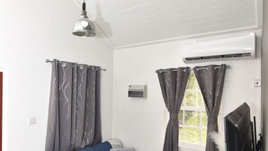 Un salon moderne avec un canapé d’angle, un téléviseur à écran plat et un ventilateur de plafond.