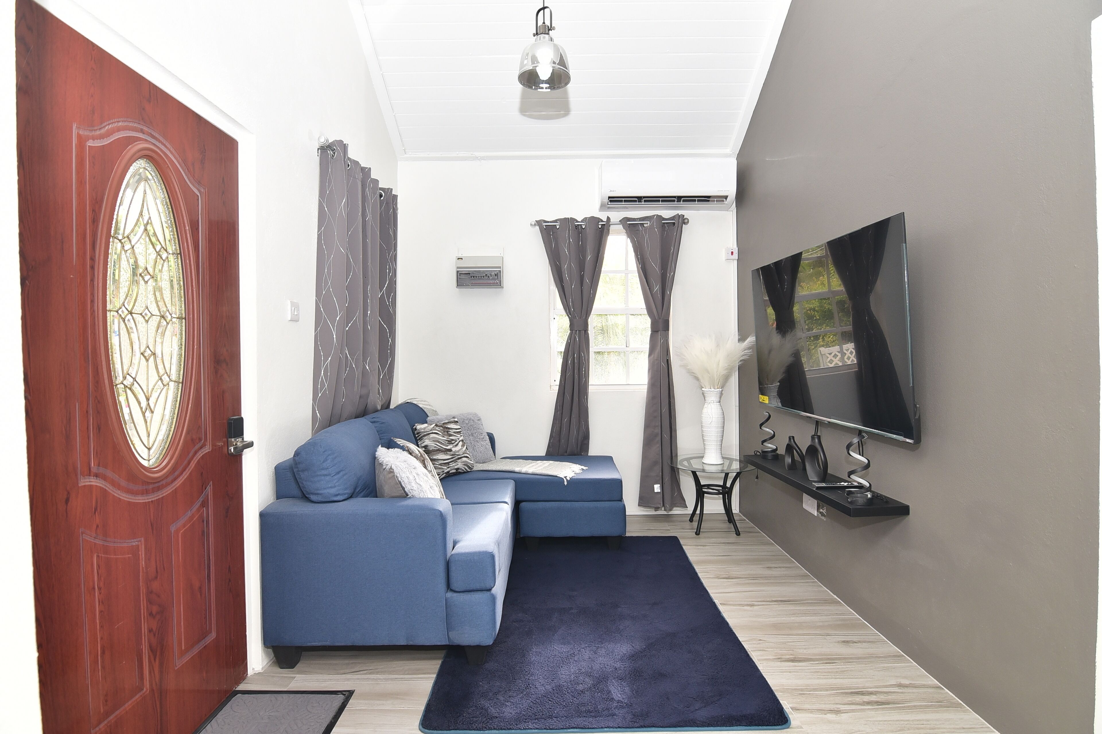 Een moderne woonkamer met een blauwe bank, een flatscreen televisie en een decoratieve vaas.
