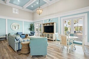 A spacious living room with a sectional sofa, a television, and a dining area with white chairs and a table. - 251 Cinnamon Beach (Palm Coast)