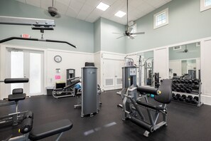 A gym with exercise equipment, a clock, and an exit sign. - 251 Cinnamon Beach (Palm Coast)