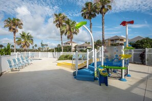 A children's play area with slides, climbing structures, and a poolside seating area. - 251 Cinnamon Beach (Palm Coast)