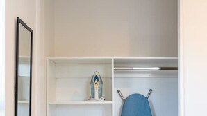 Ein begehbarer Kleiderschrank mit Regalen, einer Kleiderstange und einem kleinen Bügelbrett.