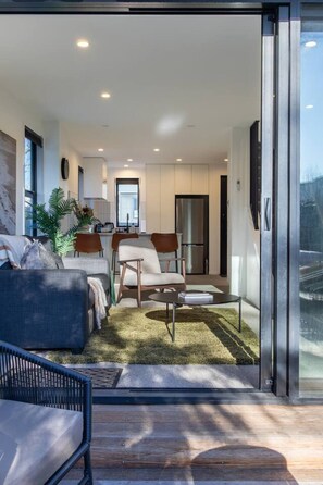 A modern interior with a sofa, armchair, and a dining table. - Peaceful Merivale Hideaway - Parkside + Parking (Christchurch)