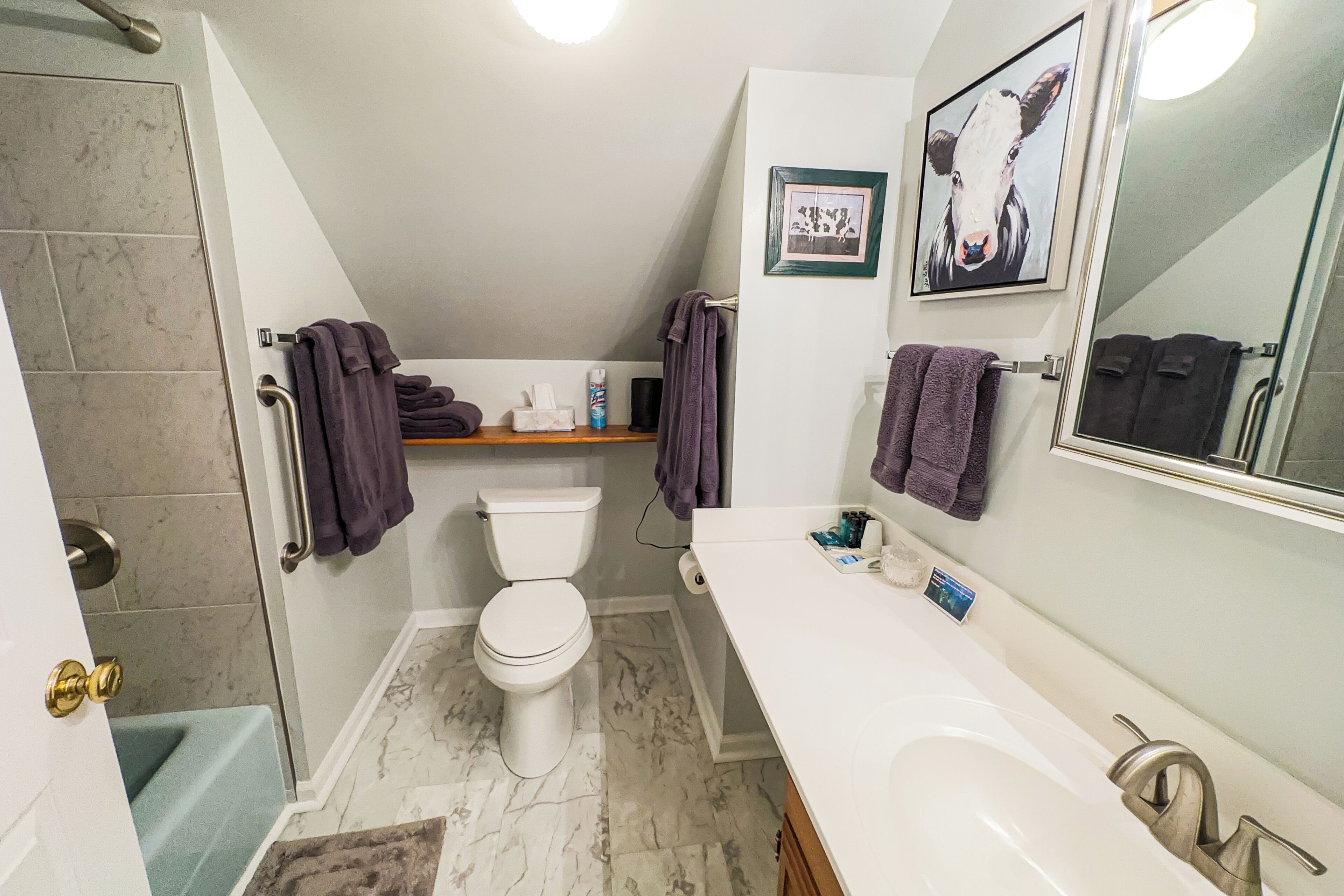 A bathroom with a toilet, sink, and shower. There are towels and toiletries on the counter.