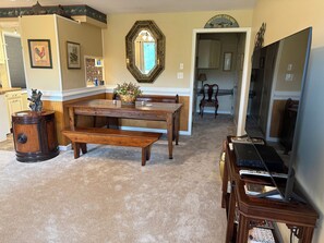 A dining area with a wooden table and benches, a decorative mirror, and a piano.
