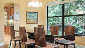 Un'area pranzo con tavolo e sedie, un quadro appeso al muro e una finestra vista alberi.