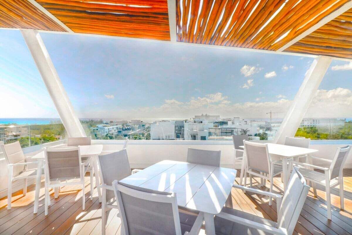 An outdoor terrace with a table and chairs, overlooking a cityscape.