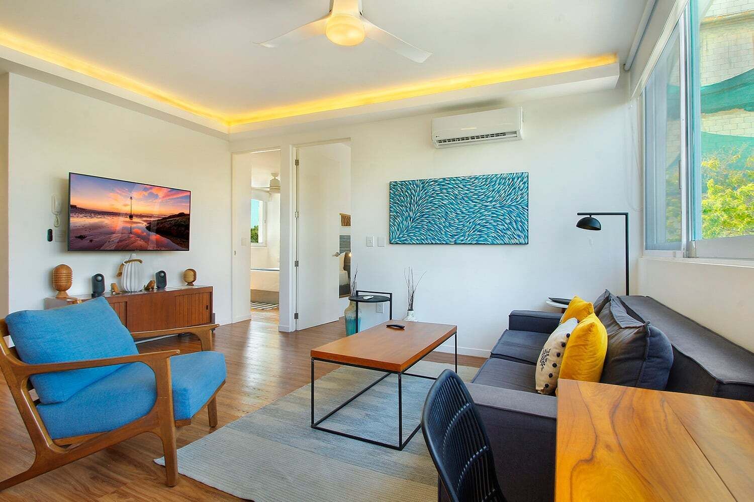 Un salon moderne avec un téléviseur à écran plat, une table basse, un canapé et une table à manger.